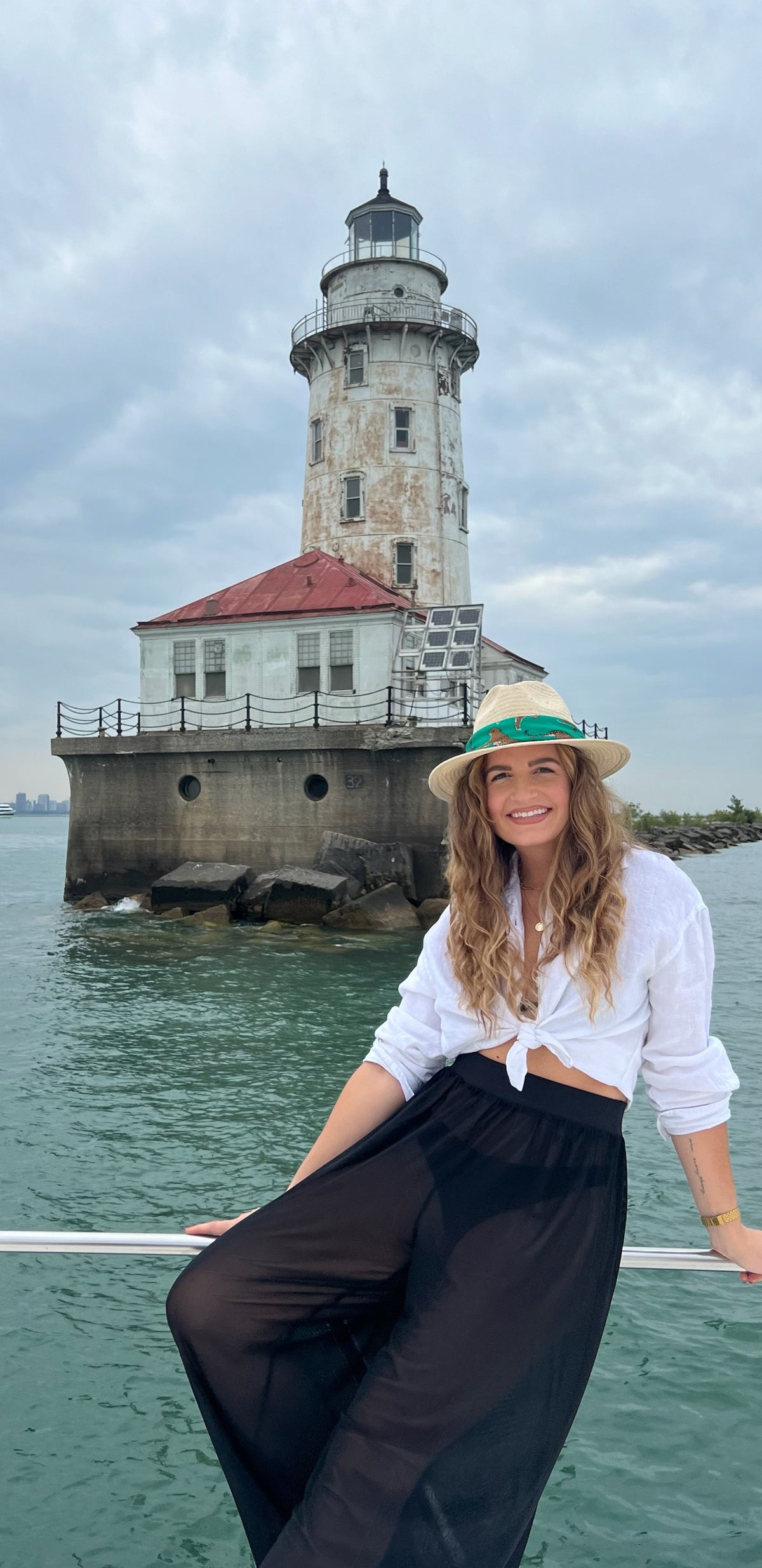 picture of woman leaning on rail in front of old lighthouse.